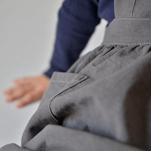 Kids pinafore apron in charcoal, linen and cotton fabric, tie back and roomy pockets in front